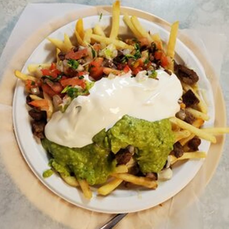 Carne asada fries from Taqueria Los Gordos, topped with guacamole, sour cream, and pico de gallo.