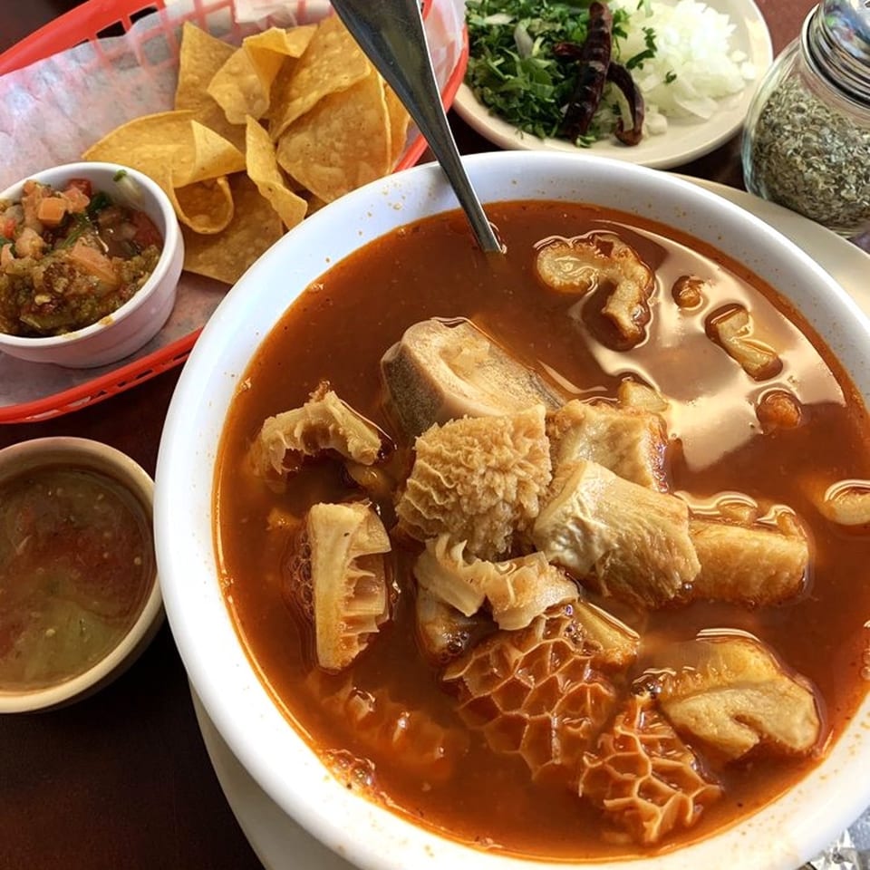 Menudo soup with tripe, served with tortilla chips, salsa, and chopped onions.