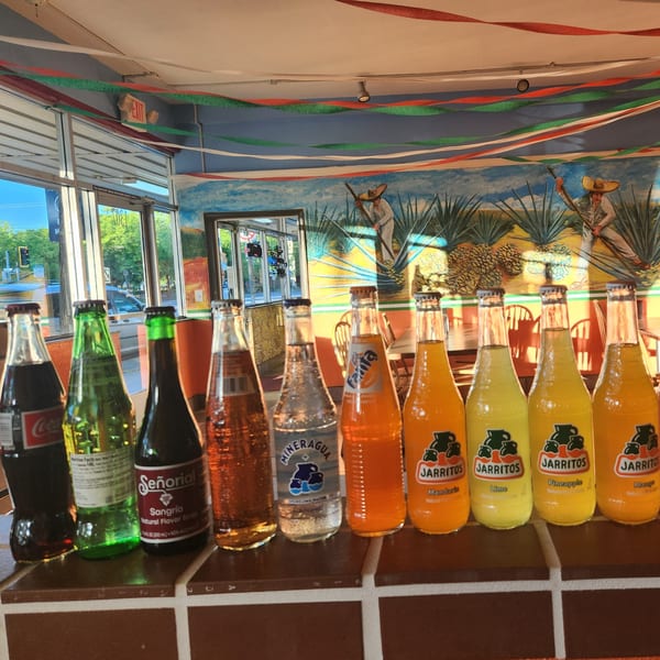 A row of Mexican sodas, including Jarritos and Sangria, on a counter in Taqueria Los Gordos.