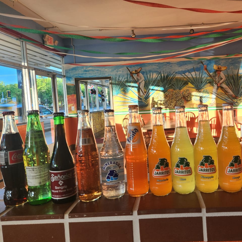 A row of Mexican sodas, including Jarritos and Sangria, on a counter in Taqueria Los Gordos.